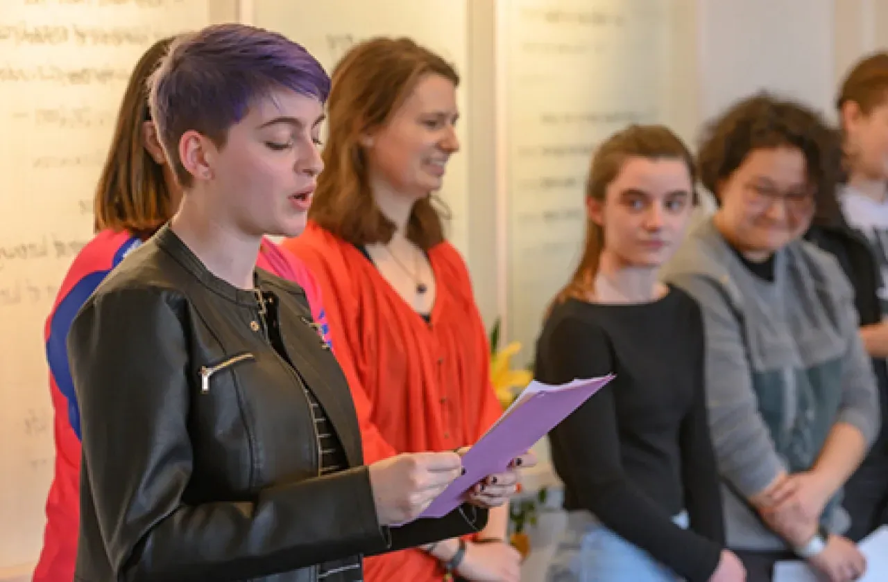 A student reading poetry to a gathered group